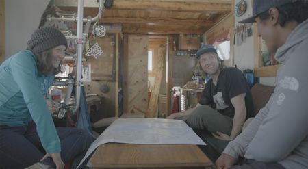 Polar Explorer Sarah McNair-Landry, left, and her partner Erik Boomer sit inside their tiny home discussing expeditions with Jimmy Chin, right.  (photo credit: National Geographic /Ross McDonnell)
