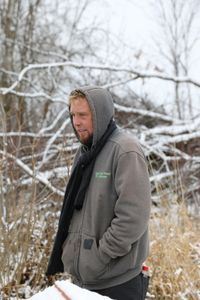 Ben Reinhold stands outside in the snow at the Pol family's farm while moving hay bales to protect the bee hives from strong winter winds. (National Geographic)