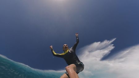 Justine Dupont raises her arms triumphantly as she emerges from the tube of a giant wave at Jaws.  (Mandatory photo credit: Justine Dupont)