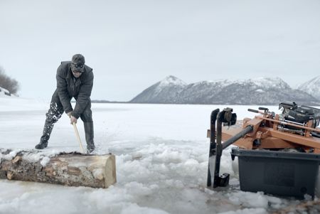 Joel Jacko chops wood to mill into planks. (National Geographic/Wayne Shockey)