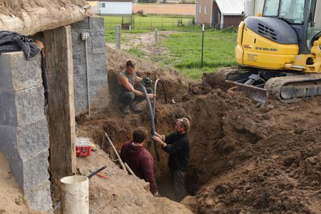 Scott Brady, Andrew Hutton, and Ben Reinhold move the water pipe in the sheep hut to provide better drainage inside. (National Geographic)