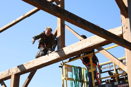 Ben Reinhold uses a crowbar to take down the beams from the old barn as Charles Pol assists him from a lift. (National Geographic)