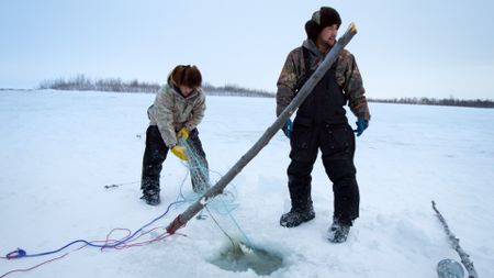 Avery and Gage Hoffman pull their fish nets under the ice. (BBC Studios/Danny Day)