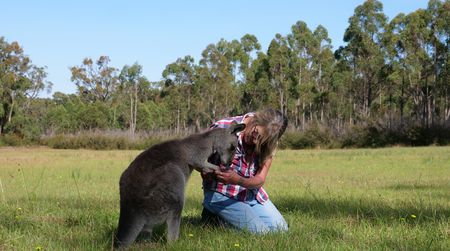 Theresa Matthews sits in a field with a kangaroo. (Big Wave Productions)