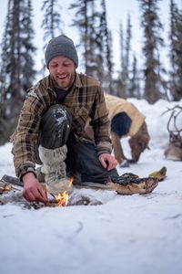 Johnny Rolfe adds kindling to a fire while he builds a box seat for his dog, Java. (BBC Studios Reality Production/Patrick Henderson)