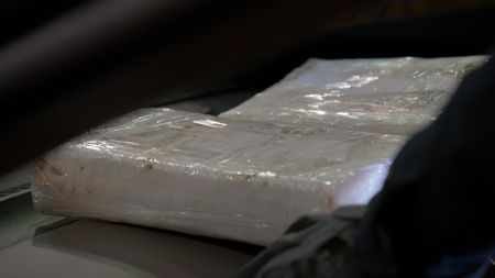 Packages of suspected narcotics are resting on the dashboard of a suspect's vehicle after they were discovered smuggled inside the center console. (National Geographic)