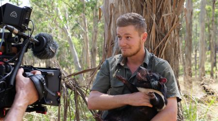 Tyler holding a tasmanian devil while being filmed. (Big Wave Productions)