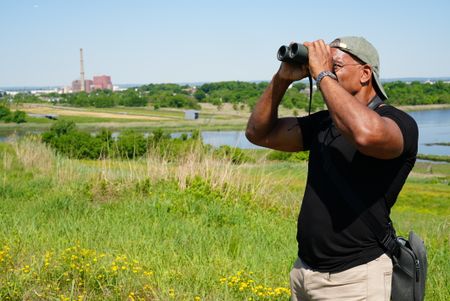 Christian Cooper looks through binoculars at Freshkills Park. (National Geographic/Troy Christopher)