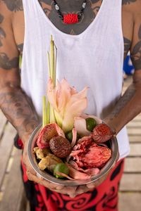 Peter holds a dish filled with buah maram, lemongrass, torch ginger and other ingredients. (Credit: National Geographic/Annice Lyn)