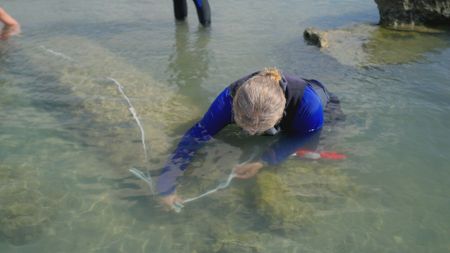 Prof. Beverley Goodman measures the dimensions of a submerged column at Herod's palace in Caesarea, Israel. (Windfall Films)