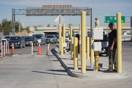 A member of the field team looks on as multiple vehicles wait  in line to cross at the El Paso border in El Paso, Texas. (National Geographic)