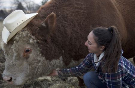 Laura petting a bull who is wearing a cowboy hat. (Big Wave Productions)