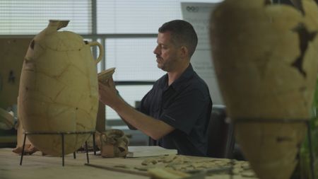 Ido Koch looks over previously found artifacts at the Tel Aviv University in Tel Aviv, Israel. (Windfall Films/Nava Mizrahi)