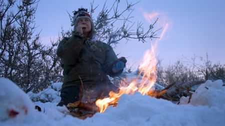 Sue Aikens cooks a ptarmigan by the fire for her dinner. (BBC Studios/Michael Cheeseman)