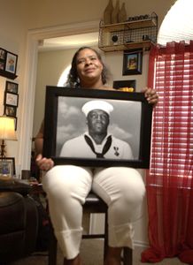 Salena James holds a portrait of her great uncle Doris Miller at Flosetta Miller's home in Arlington, Texas. "Erased: WW2's Heroes of Color" tells the stories of three Black heroes who miraculously survived the attack on Pearl Harbor. One of these men, mess attendant Doris Miller, defied racial stereotypes when he shot down enemy planes during the attack. (National Geographic/Nelson Adeosun)