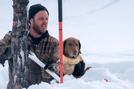 Johnny Rolfe and his dog Java collect ice glacial water by chipping clear ice blocks from the river. (BBC Studios Reality Production/Patrick Henderson)