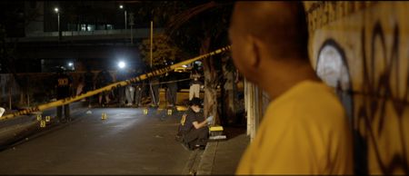 Manila, Philippines - A man observes a crime scene in the distance. (Genius Loki Film and Violet Films/Alexander A. Mora)