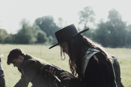 Geillis Duncan is kneeling over a grave, she is holding and examining the remains of a human arm. (Dash Productions Services LTD/Antoan Ivanov)