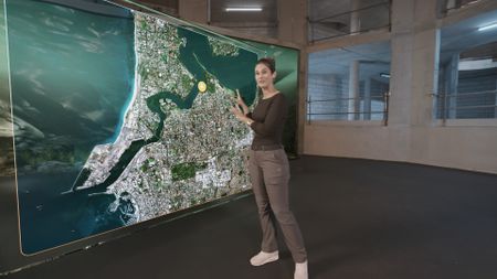 Dr. Diva Amon pointing at a GFX map while in the shark studio lab. (National Geographic)