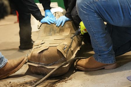 Multiple CBP officers work to dismantle the gas tank of a suspect's vehicle after packages of suspected narcotics were seen on a camera scope in Calexico, Calif. (National Geographic)