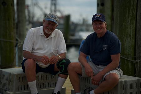 Jack Casey and Dr. Greg Skomal sit next to each other smiling on a pier in Martha Vineyard. (National Geographic/Brandon Sargeant)