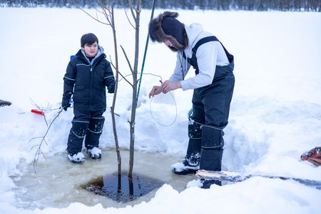 Ricko DeWilde teaches his son Keenan DeWilde how to properly set a beaver trap under the ice. (BBC Studios Reality Productions/v)