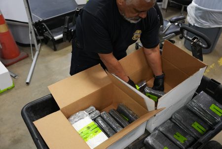 CBP Officer Martinez sorts and stacks packages of suspected narcotics  found in the reefer unit of a tractor trailer in Rio Grande Valley,  Texas. (National Geographic)