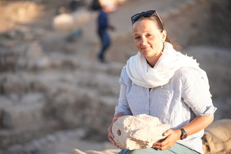 Katharina Schmidt examines the recently unearthed stone head at the citadel excavation site in Amman, Jordan. (Windfall Films/Alex Collinge)