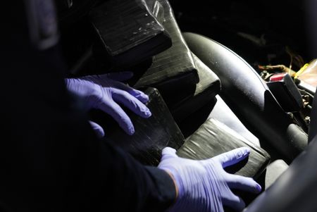 Multiple packages of suspected narcotics are being stacked on the driver's seat of a suspect's vehicle after they were found smuggled inside in Brownsville, Texas. (National Geographic)