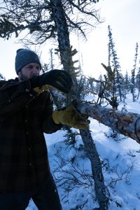 Johnny Rolfe sets a conibear trap on a tree before the trapping season comes to an end. (BBC Studios Reality Productions, LLC/Tyler Colgan)