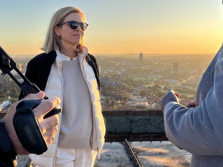 Mariana van Zeller and Ben discuss the world of scamming while on a rooftop in Johannesburg. (National Geographic for Disney)
