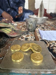 Gold coins are weighed on a scale in Niger. (National Geographic for Disney)