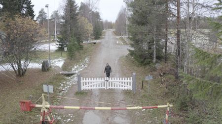 Drone shot of man walking to a white gate. (National Geographic)