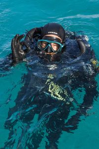 Director and cinematographer Adam Geiger, on a closed-circuit rebreather, gives an 'ok' sign as he prepares to dive down and film with a Mimic octopus.  (National Geographic for Disney/Harriet Spark)