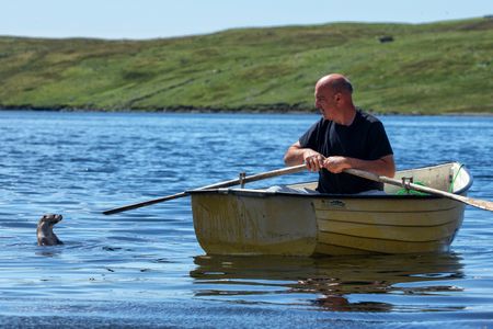 Billy and Molly sit in Billy's rowing boat in the sea just off West Shetland. (National Geographic/Johnny Rolt)