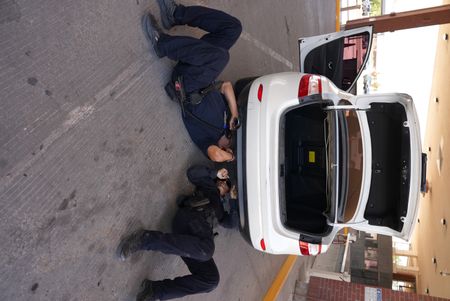 Two CBP officers inspect under the back bumper of a suspect's vehicle after it was sent to secondary in El Paso, Texas. (National Geographic)