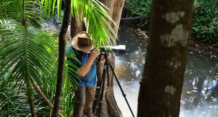 Neil Andison stands at edge of the Obi Creek in Australia taking pictures of a platypus. (Big Wave Productions)