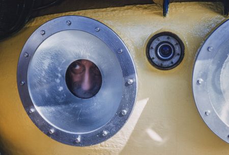 BECOMING COUSTEAU - Jacques Cousteau peers out of the porthole of SP-350 Denise diving saucer, 1960. (Credit: National Geographic/Luis Marden)