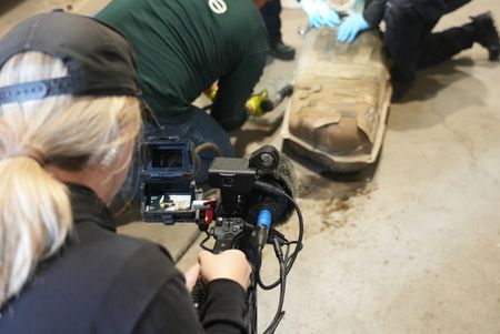 A cameraman films multiple CBP officers work to dismantle the gas tank of a suspect's vehicle after packages of suspected narcotics were seen on a camera scope in Calexico, Calif. (National Geographic)