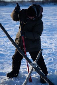 Avery Hoffman picks a hole in the ice to set their fish nets. (BBC Studios Reality Productions, LLC/Isaiah Branch - Boyle)