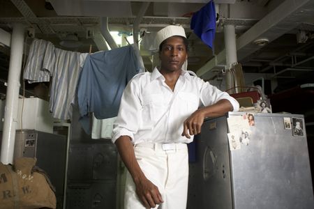 Mess attendant Clark Simmons (played by Actor Kyle Reece Bell) poses for a portrait in a WW2 historic reenactment scene for "Erased: WW2's Heroes of Color. The series tells the stories of three Black heroes who miraculously survived the attack on Pearl Harbor. One of these men is Clark Simmons, who served as mess attendant on the USS Utah (National Geographic/Seye Isikalu)