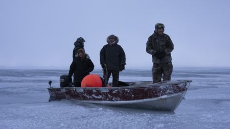 Chris, Daniel and Nalu Apassingok, along with their family member Ala on a boat, searching for seals. (National Geographic/Zach Clanton)