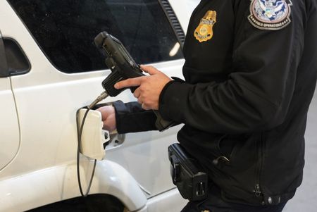 A CBP officer uses a camera scope to better see the inside of the gas tank of a suspect's vehicle in Calexico, Calif. (National Geographic)