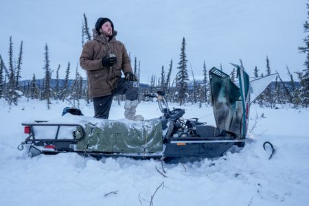 Johnny Rolfe fixes his snowmobile after it breaks down in the deep snow. (BBC Studios Reality Productions/Tyler Colgan