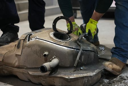 Multiple CBP officers work to dismantle the gas tank of a suspect's vehicle after packages of suspected narcotics were seen on a camera scope in Calexico, Calif. (National Geographic)