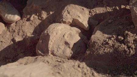 A stone head is discovered during the excavations at the Citadel in Amman. (Windfall Films)