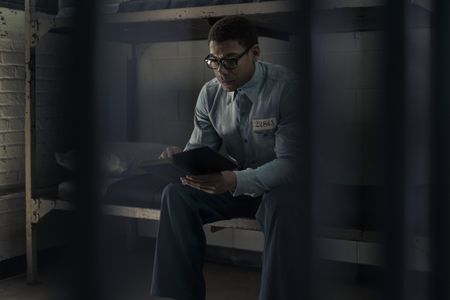 Malcolm X, played by Aaron Pierre, reads the Quran in prison in GENIUS: MLK/X. (National Geographic/Richard DuCree)