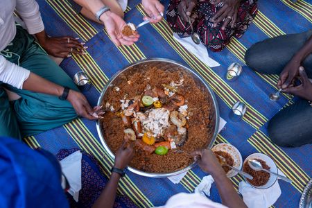 Everyone gathers around to taste the Ceebu jën. (National Geographic/John Wendle)