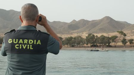 A guard scans the horizon with binoculars in Almeria, Spain. (National Geographic)