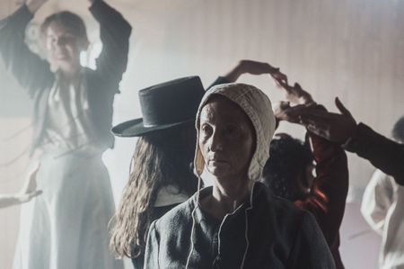 Agnes Sampson standing inside the church amongst the crowd of the witches sabbath. Agnes is staring into to the disctance. In the crowd are a few vistors and the devil. (Dash Productions Services LTD/Antoan Ivanov)